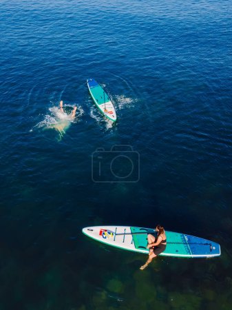 Téléchargez les photos : 24 juillet 2022. Antalya, Turquie. Couple se détendre et nager sur stand up paddle board à la mer bleue. Les gens sur la planche à pagaie rouge dans la mer Méditerranée. Vue aérienne - en image libre de droit