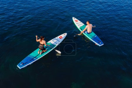 Photo for July 24, 2022. Antalya, Turkey. Couple relax on stand up paddle board at blue sea. People on Red paddle sup board in Mediterranean sea. Aerial view - Royalty Free Image