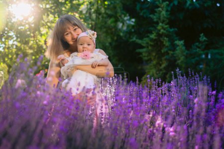 Foto de Joven hermosa madre con su hijo jardín al aire libre con flores de lavanda y sol - Imagen libre de derechos