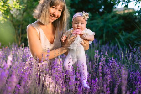 Photo for Happy mother with her baby in garden with lavender flowers and sunshine - Royalty Free Image