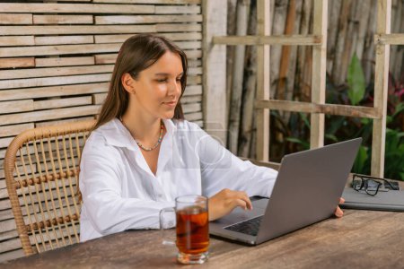 Téléchargez les photos : Femme pigiste utilisant un ordinateur portable assis dans le bureau tapant sur un ordinateur portable. - en image libre de droit