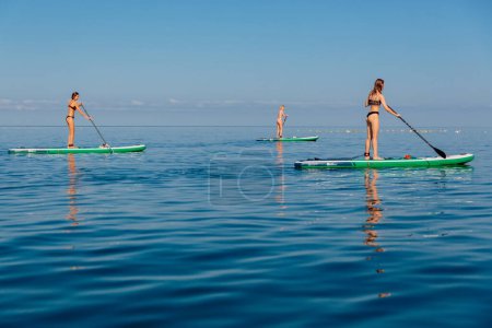 Téléchargez les photos : 30 juillet 2022. Budva, Monténégro. Groupe de femmes debout planche à pagaie à la mer bleue. Femmes flottant sur Red Paddle SUP board dans l'océan. - en image libre de droit