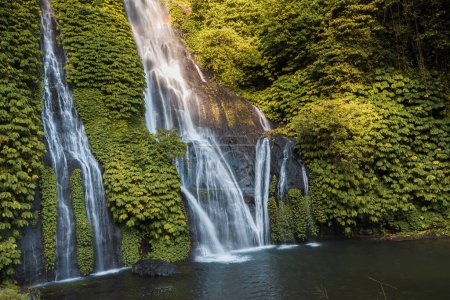 Téléchargez les photos : Cascade de jungle en cascade dans la forêt tropicale humide avec roche et étang de cristal. Cascade panoramique avec eau bleue cristalline et arc-en-ciel sous les tropiques. - en image libre de droit
