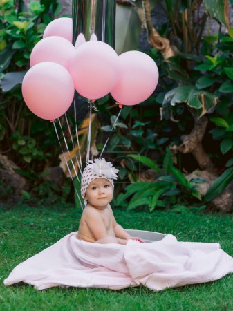 Foto de Niña feliz y globos de aire rosa nadan en el jardín al aire libre del baño del bebé. - Imagen libre de derechos