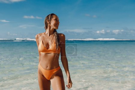 Téléchargez les photos : Belle femme bronzée en bikini à la plage de l'océan tropical. - en image libre de droit