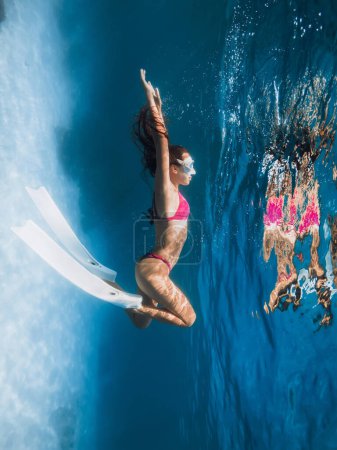 Téléchargez les photos : Slim femme freediver avec des nageoires relaxantes sous l'eau. Plongée en apnée dans l'océan bleu tropical - en image libre de droit