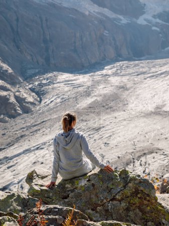 Foto de Senderista mujer relajarse en piedra cerca de las montañas con glaciar - Imagen libre de derechos