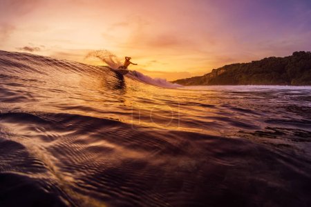 Téléchargez les photos : 14 décembre 2022. Bali, Indonésie. Homme dans l'océan tropical pendant le surf avec des tons de coucher ou de lever du soleil. Surfer sur la vague et faire des tours. - en image libre de droit