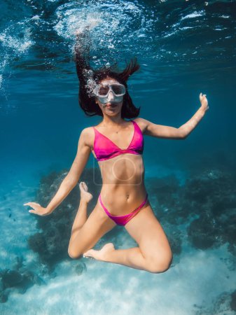Photo for Young woman in pink bikini fun underwater in transparent ocean. - Royalty Free Image