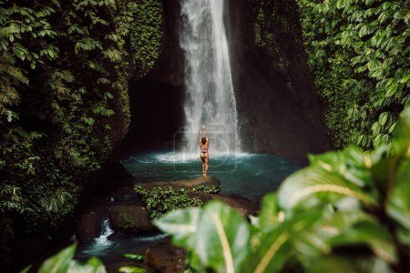 Téléchargez les photos : Scenic waterfall and woman in bikini near waterfall. Traveler girl posing on waterfall - en image libre de droit