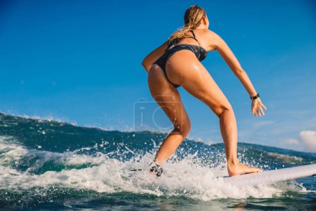 Photo for Behind view of attractive surf girl at surfboard on ocean wave. - Royalty Free Image