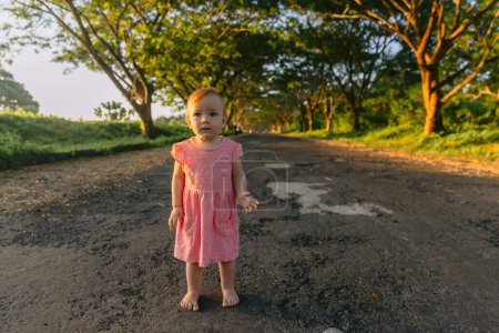 Foto de Hermosa niña en el exterior con luz del atardecer. Lindo bebé en vestido rosa en el parque. - Imagen libre de derechos