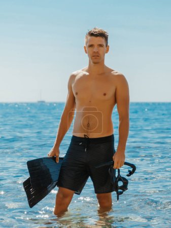 Téléchargez les photos : Bel homme mince profiter de la journée sur la plage après la plongée en apnée. - en image libre de droit