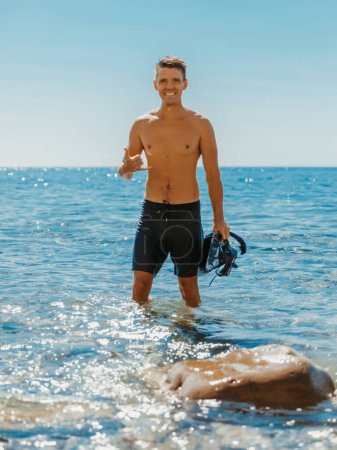 Téléchargez les photos : Beau seins nus mâle modèle vacances sur la plage de l'océan. Homme sportif souriant après la plongée - en image libre de droit
