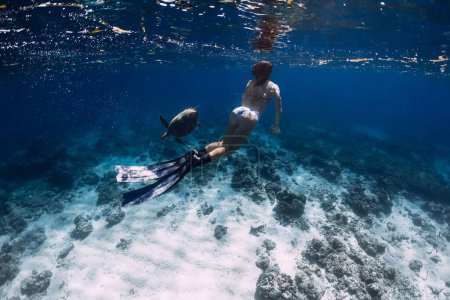 Téléchargez les photos : Femme plongeur sous-marin nageant avec tortue sous-marine dans un océan transparent - en image libre de droit