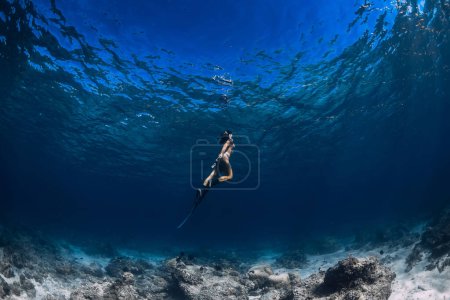 Foto de Mujer libre se desliza bajo el agua en el océano. Freediver en las aguas cristalinas - Imagen libre de derechos