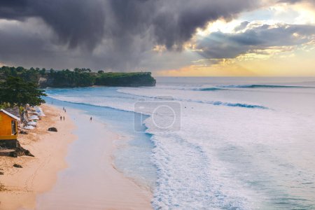 Téléchargez les photos : Plage de vacances à Bali avec coucher de soleil pittoresque et océan avec vagues de surf - en image libre de droit