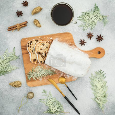 Photo for Christmas composition with tasty stollen cake on a wooden board, cutlery and coffee cup on gray table - Royalty Free Image