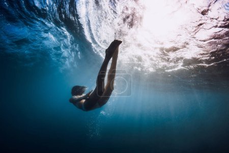 Foto de Mujer nadando bajo el agua con olas oceánicas y rayos de sol. - Imagen libre de derechos