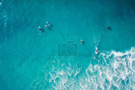 Téléchargez les photos : Surfeurs sur planches de surf dans l'océan turquoise transparente vague d'attente. Vue aérienne - en image libre de droit