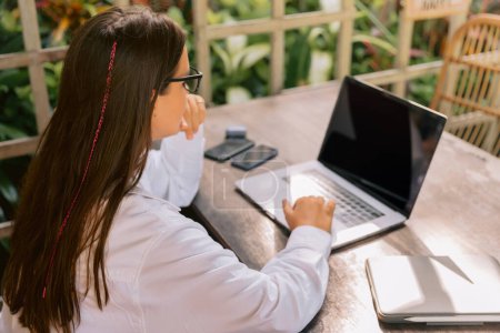 Téléchargez les photos : Jeune femme d'affaires travaillant sur ordinateur portable dans un café extérieur - en image libre de droit