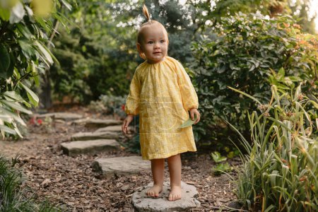 Foto de Linda niña en vestido elegante en el jardín del patio trasero. Niño niña al aire libre. - Imagen libre de derechos