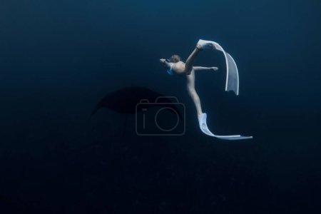 Foto de La mujer nada bajo el agua con manta ray. Freediving con manta rayas en el océano profundo - Imagen libre de derechos