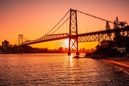 Hercilio luz cable bridge with warm sunset and bay waters in Florianopolis