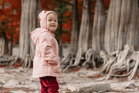 Téléchargez les photos : Mignon enfant fille jouer dans un parc automnal avec des orangers. - en image libre de droit