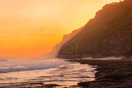 Téléchargez les photos : Côtes avec océan orageux, vagues et soleil chaud au coucher du soleil - en image libre de droit