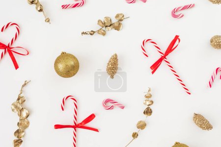 Foto de Composición de Navidad con decoración dorada y bastones de caramelo sobre blanco. Piso tendido, vista superior - Imagen libre de derechos