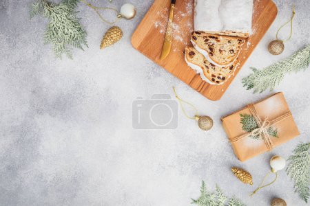 Téléchargez les photos : Table de Noël avec gâteau gonflé de célébration sur une planche en bois, couverts et boîte cadeau en papier sur gris. Couché plat, vue du dessus - en image libre de droit