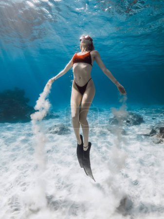 Foto de Freediver nada bajo el agua y juega con arena. Freediving con mujer atractiva en el océano azul tropical - Imagen libre de derechos
