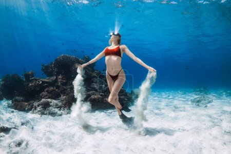 Téléchargez les photos : Freediver nage sous l'eau et joue avec le sable. Plongée sous-marine avec une femme attrayante en mer bleue claire - en image libre de droit