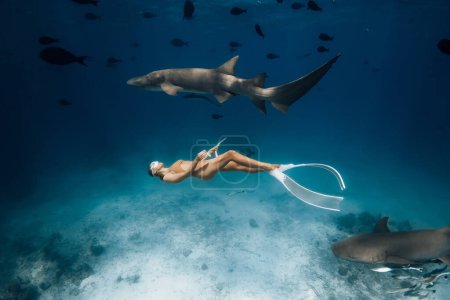 Foto de Mujer nadando con los tiburones en un mar tropical en las Maldivas. - Imagen libre de derechos