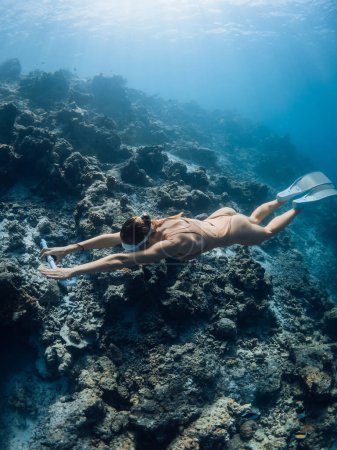 Téléchargez les photos : Femme formation de plongeur en apnée sur les profondeurs de l'océan bleu. Une plongeuse nage sous l'eau - en image libre de droit