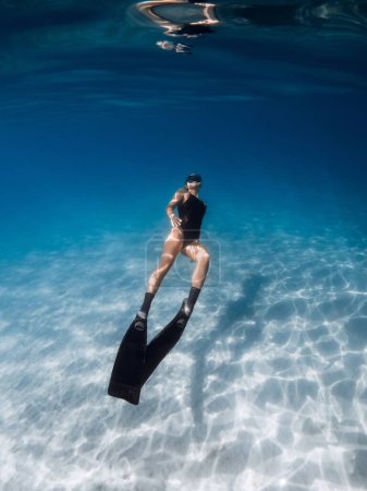 Téléchargez les photos : Plongeur sous-marin nageant en mer tropicale sur fond sablonneux. Nage féminine avec nageoires sous-marines - en image libre de droit