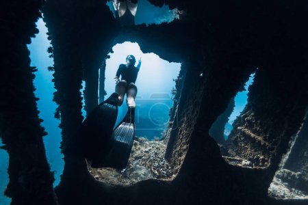Foto de La libre mujer nada bajo el agua entre las ruinas de un barco. Freediving en un barco naufragado - Imagen libre de derechos