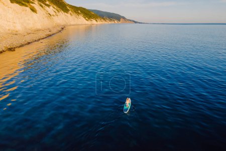 Téléchargez les photos : Femme à bord du SUP à la mer calme avec paysage méditerranéen pittoresque. Vue aérienne - en image libre de droit
