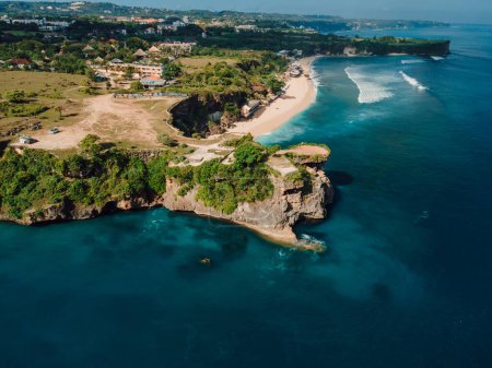Aerial view of sandy beach with scenic rock and ocean in Bali