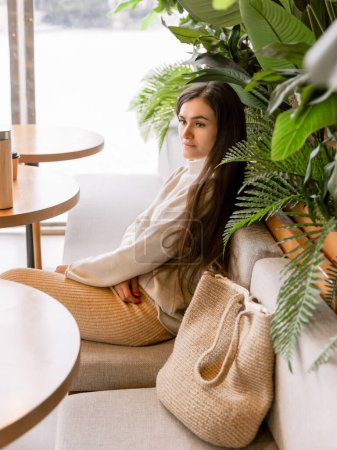 Téléchargez les photos : Belle femme avec un sac de paille assis dans un café - en image libre de droit