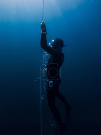 Foto de Marzo 04, 2024. Nusa Penida, Indonesia. Hombres libres en traje de neopreno entrenando bajo el agua en lo profundo del océano azul. Freediving profesional en mar transparente - Imagen libre de derechos