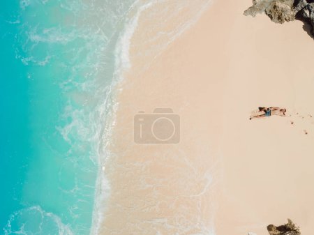 Handsome man sunbathing at tropical ocean beach. Aerial view Stickers 708734534
