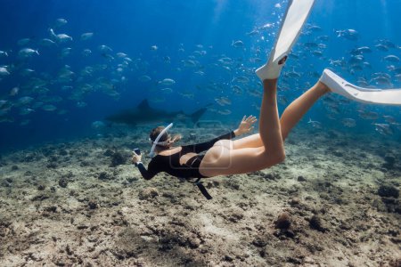 Mujer sumergirse al tiburón tigre en el océano azul en las Maldivas.