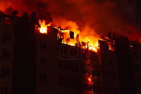 Téléchargez les photos : La maison en feu est engloutie dans les flammes. Incendie dans l'immeuble. - en image libre de droit