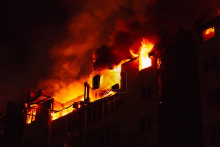 Foto de La casa en llamas está envuelta en llamas. Incendio en edificio de apartamentos. - Imagen libre de derechos