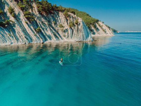 Photo for Man on stand up paddle board in blue sea in Mediterranean sea with scenic landscape. Aerial view - Royalty Free Image