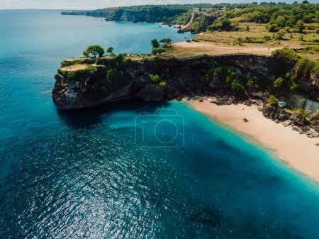 Téléchargez les photos : Vue aérienne de la plage de sable avec roche pittoresque et océan bleu à Bali - en image libre de droit