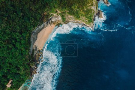 Téléchargez les photos : Paysage pittoresque avec plage cachée et océan bleu avec vagues en Indonésie. Vue aérienne. - en image libre de droit