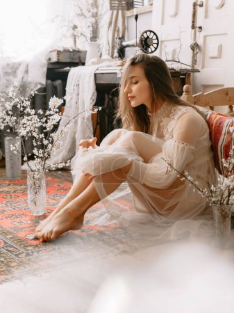 Photo for Young elegant fashionable model wearing vintage bridal dress sitting on floor, posing at home, in stylish vintage interior - Royalty Free Image